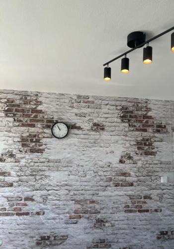 a clock on the side of a brick wall with lights at Kemi CITY III near snowcastle, premium 2 rooms , kitchen , glazed balcony, FREE private parking in Kemi