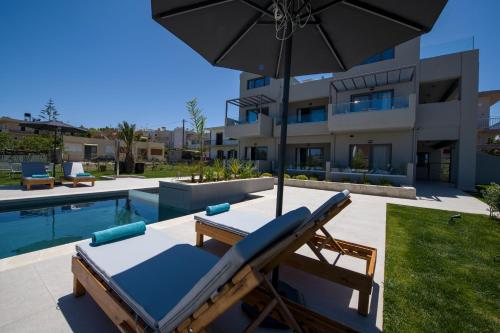 un patio con sillón y sombrilla junto a la piscina en Eleanthi Modern Living en Galatás