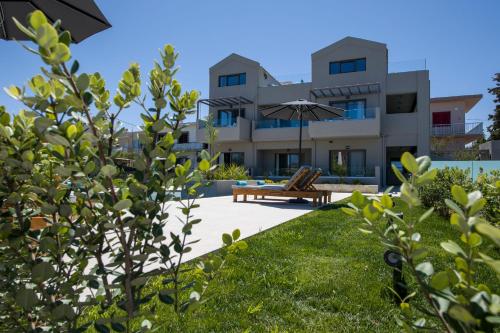 einen Blick auf ein Haus aus dem Garten mit einer Bank und einem Regenschirm in der Unterkunft Eleanthi Modern Living in Galatás