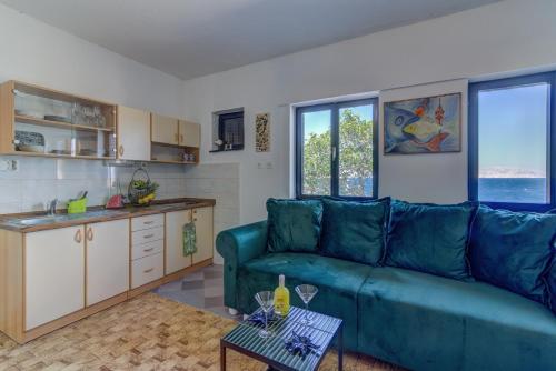 a living room with a blue couch and a kitchen at Casa al mare in Sveti Juraj