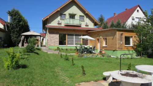 a house with a green yard with a table at Hőforrás Wellness Vendégház in Egerszalók