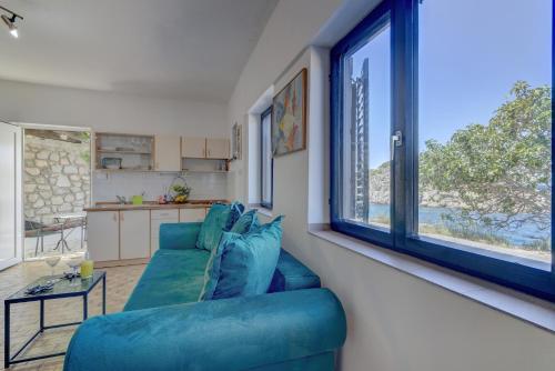 a living room with a blue couch and a kitchen at Casa al mare in Sveti Juraj