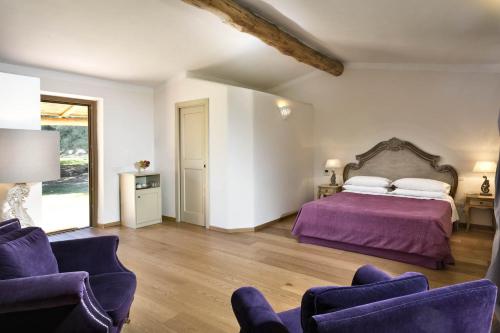 1 dormitorio con 1 cama de color púrpura y 2 sillas en Stazzo Lu Ciaccaru, en Arzachena