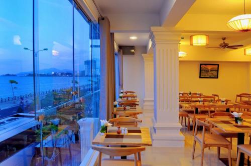 a restaurant with tables and chairs and a large window at Iridescent Clouds Hotel Nha Trang -Mây Ngũ Sắc in Nha Trang