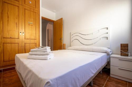 Un dormitorio con una cama blanca con toallas. en Apartamentos Alma de Zahara, en Zahara de los Atunes
