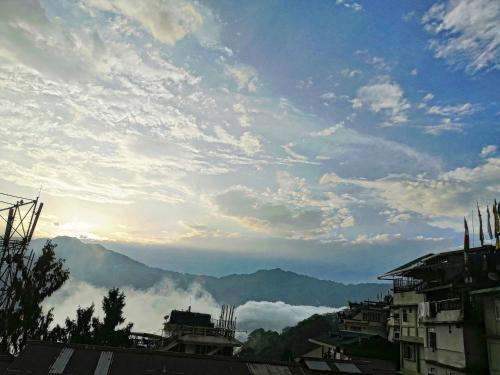 a cloudy sky with mountains in the background and buildings at Hotel Nindik in Gangtok