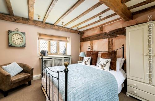 a bedroom with a bed and a chair and a clock at Little Gables in Broadway