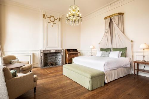 a bedroom with a bed and a fireplace and a chandelier at De Tuilerieën - Small Luxury Hotels of the World in Bruges
