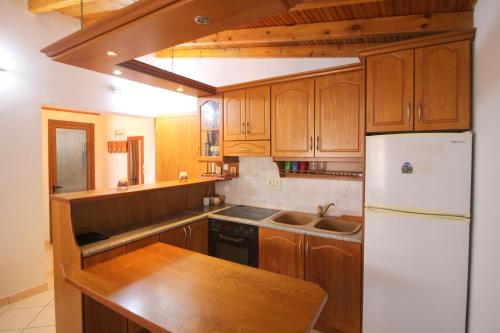 a kitchen with wooden cabinets and a white refrigerator at Alex Apartments in Sarandë