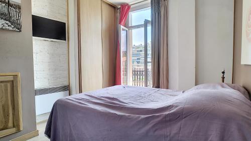 une chambre avec un lit et une grande fenêtre dans l'établissement Superbe appartement vue dégagée sur des jardins, à Cannes