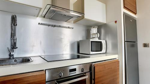 une cuisine avec un évier et un micro-ondes dans l'établissement Superbe appartement vue dégagée sur des jardins, à Cannes