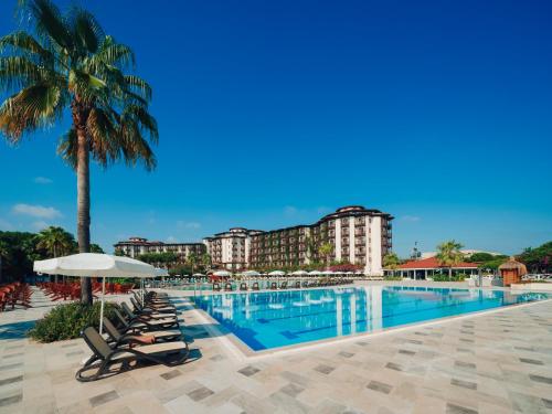 a pool at a resort with chairs and a palm tree at Selectum Family Resort Belek in Belek