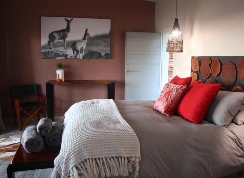 a bedroom with a large bed with red pillows at Mountain Peak Game Lodge and Camping in Ozongaka