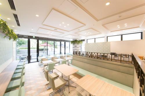 a restaurant with tables and chairs and windows at Hotel Keihan Yodoyabashi in Osaka