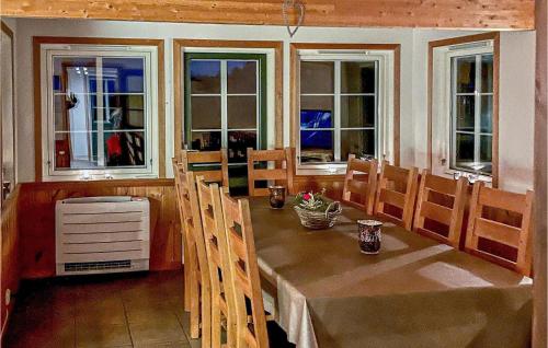 a dining room with a table and chairs and windows at Awesome Home In Spangereid With Sauna in Spangereid