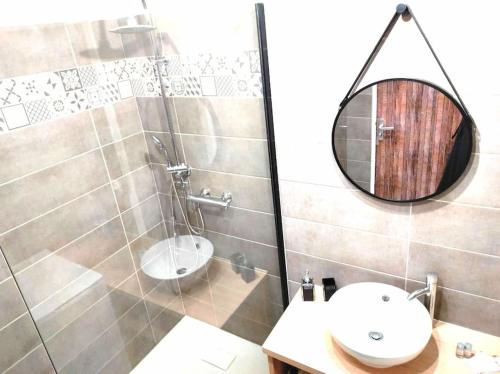La salle de bains est pourvue d'un lavabo et d'un miroir. dans l'établissement L'Antique SPA: jacuzzi sous patio, à Orange