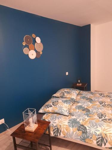 1 dormitorio con cama y pared azul en Le travers (centre ville Joigny), en Joigny