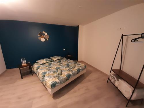 1 dormitorio con cama y pared azul en Le travers (centre ville Joigny), en Joigny