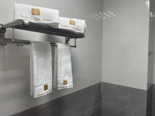 La salle de bains est pourvue de serviettes blanches suspendues à un portant. dans l'établissement Season Inn Hotel Apartment_Duqm, à Duqm