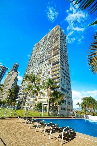 a tall building with chairs in front of a pool at Condor Apartments by Gold Coast Premium in Gold Coast