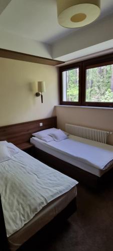 dwa łóżka w pokoju z dwoma oknami w obiekcie Apartament Perła nr 19 nad Jeziorem Pluszne w mieście Mierki