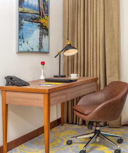 a desk with a lamp and a chair in a room at Golden Tulip Jalandhar in Jalandhar