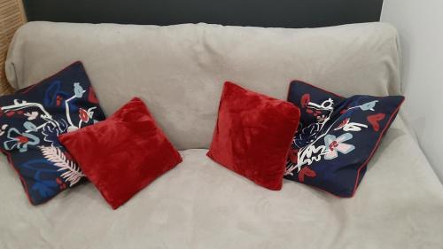 a white couch with four red pillows on it at HAPPY HoMe For You in Lunel