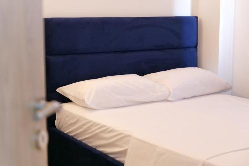 a bed with a blue headboard and two white pillows at Julies Vila in Ksamil