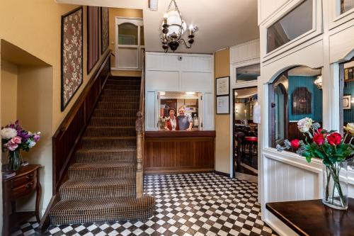 a hallway with a staircase in a home with flowers at Foley's Guesthouse & Self Catering Holiday Homes in Kenmare