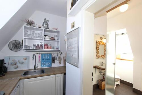 una cocina con armarios blancos y fregadero en Am Waldesrand, en Prerow
