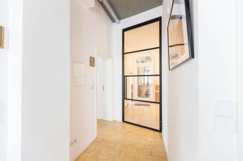 a hallway with white walls and a door with a window at Green Residence Boutique Lofts & Villa am Park in Offenbach