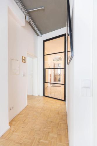 an empty room with a wooden floor and a large window at Green Residence Boutique Lofts & Villa am Park in Offenbach