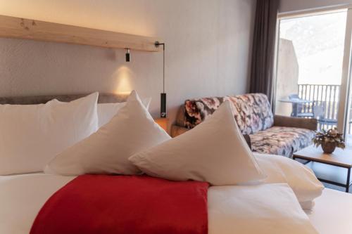 a bedroom with a bed with white pillows and a couch at Hotel Post in Prutz