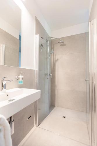 a white bathroom with a shower and a sink at Green Residence Boutique Lofts & Villa am Park in Offenbach