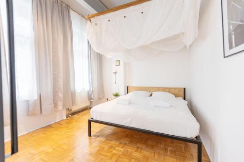 a white bedroom with a bed with white sheets and pillows at Green Residence Boutique Lofts & Villa am Park in Offenbach