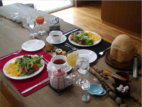 a table with plates of food and glasses of wine at Kunsthaus in Biei
