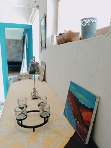 a table with glasses and a lamp and a painting at Hôtellerie Jardiniers Gourmands in Morsains