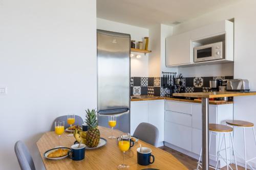 - une cuisine avec une table en bois et des verres de jus d'orange dans l'établissement Le Flamingo - Premiere conciergerie, à Palavas-les-Flots