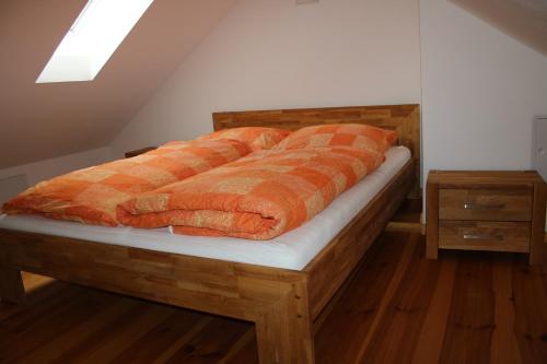 a bed with an orange blanket on top of it at Ferienwohnung Am Weltnaturerbe Grumsin in Ziehten