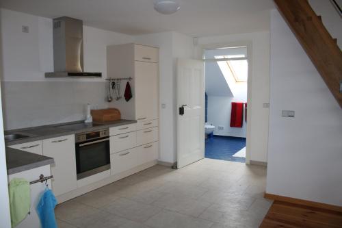 a kitchen with white cabinets and an open door at Ferienwohnung Am Weltnaturerbe Grumsin in Ziethen