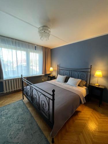 ein Schlafzimmer mit einem Bett, zwei Lampen und einer blauen Wand in der Unterkunft Cosy Teika Apartment in Riga
