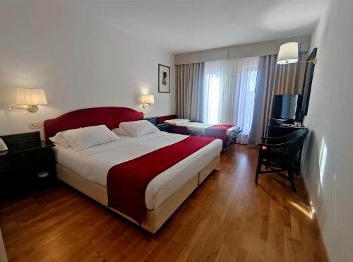 グラードにあるホテル ハノーヴァーの大型ベッドとテレビが備わるホテルルームです。