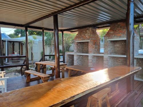 un patio con mesas de madera y bancos en una terraza en The Birdhouse Bed & Breakfast #NO Loadshedding #Solar Energy en Gonubie