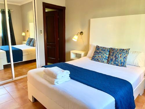 Schlafzimmer mit einem Bett mit blauer Bettwäsche und einem Spiegel in der Unterkunft Punta Cana Seven Beaches in Punta Cana