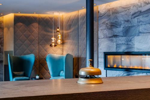 a lobby with a fireplace and blue chairs at Hotel Ideal Park in Laives
