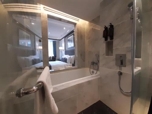 a bathroom with a tub and a shower with a mirror at Meliá Kuala Lumpur in Kuala Lumpur