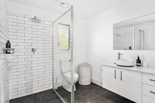 a white bathroom with a toilet and a glass shower at Adorable 1 bedroom guesthouse with firepit in Primbee