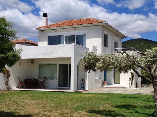 a white house with a table in a yard at V.K.Seaside Villa in Volos