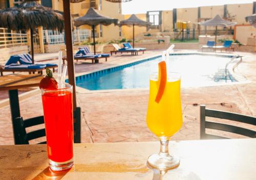 two cocktails sitting on a table next to a pool at Retal View North Coast Aqua Park in El Alamein
