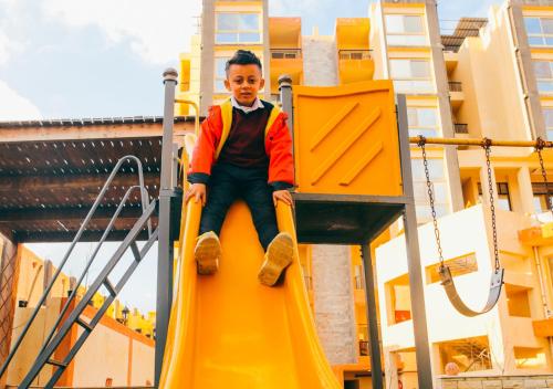 a boy sitting on a slide at a playground at Retal View North Coast Aqua Park in El Alamein
